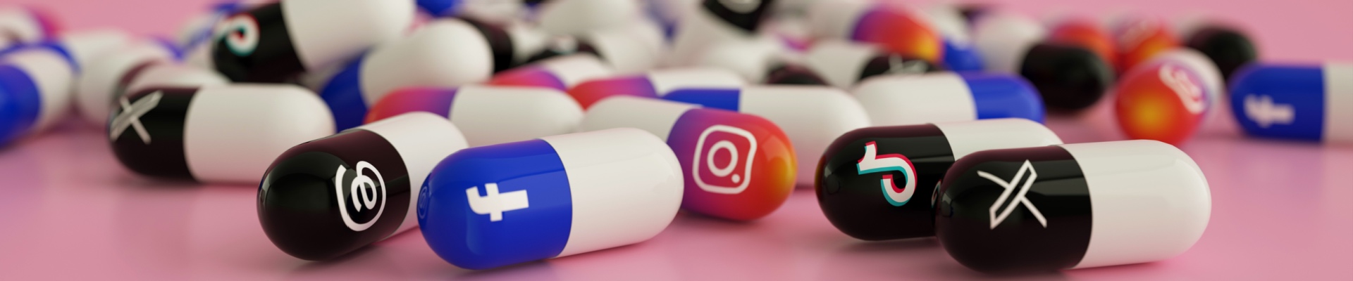 various popular social media logos as drug pills scattered on pink floor. social media addiction concept