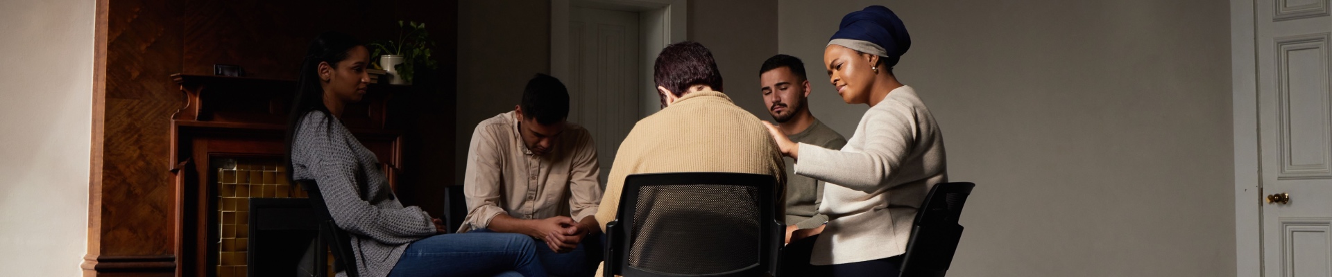 Support, group of people in therapy a community center and understanding, sharing feeling and talking in session. Mental health, addiction or depression, men and women with therapist sitting together